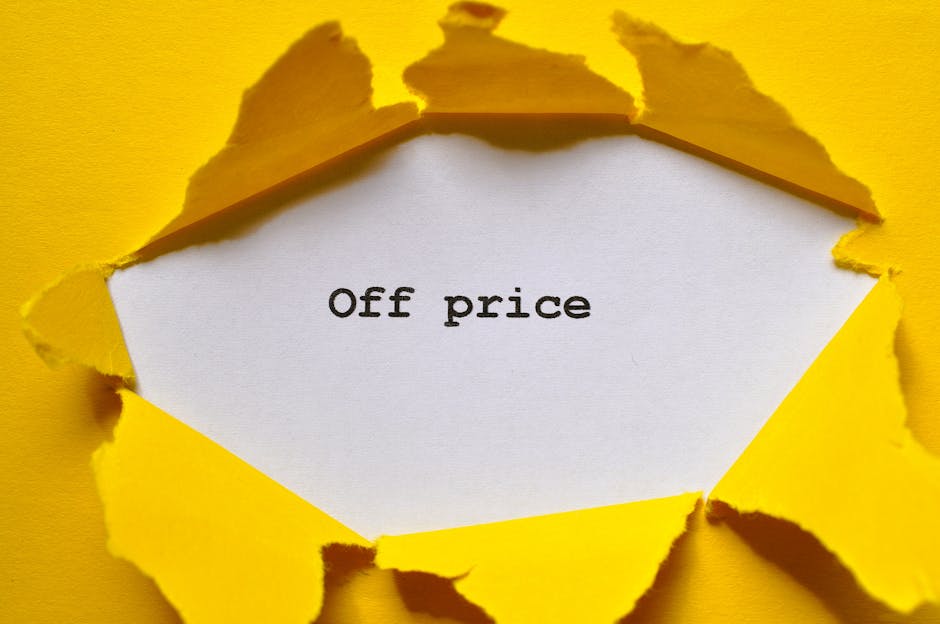 A close-up image of a bright yellow paper surface with several torn edges revealing a white background beneath. In the center, a white paper section with jagged edges is visible, displaying the black,